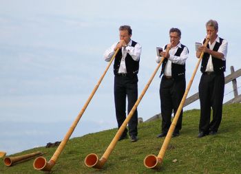Three men playing alphorns